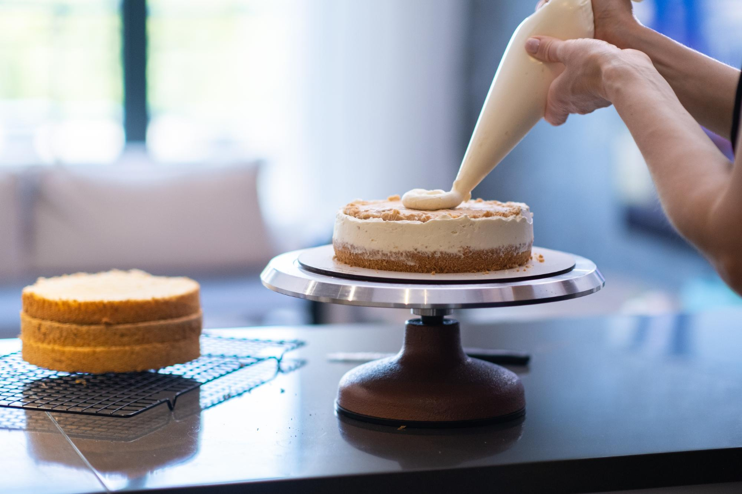 Femme faisant un gâteau fait main mettant de la crème blanche fraîche sur une couche avec un cône de pâtisserie
